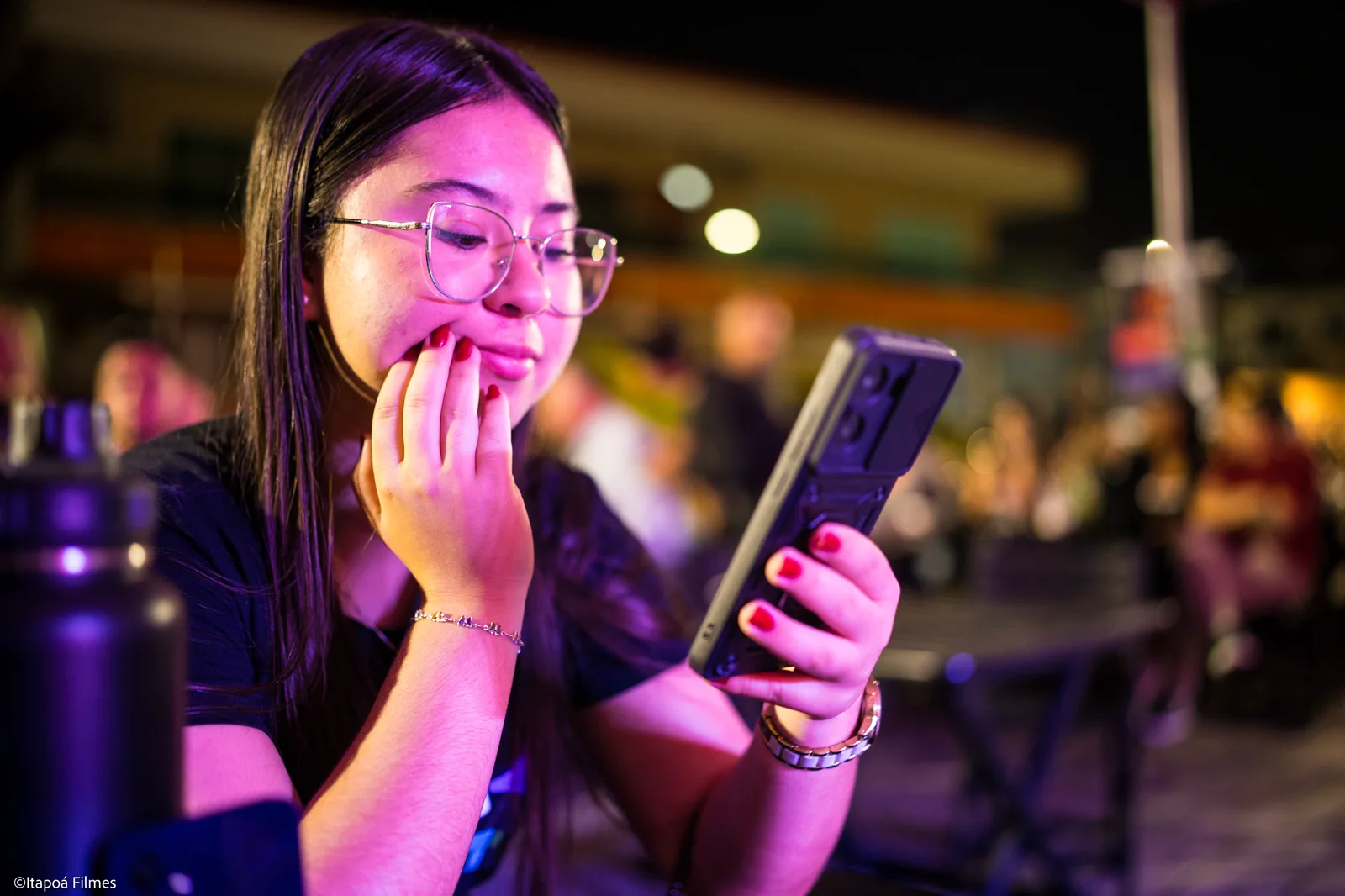 Jovem do público acompanhando o festival pelo celular